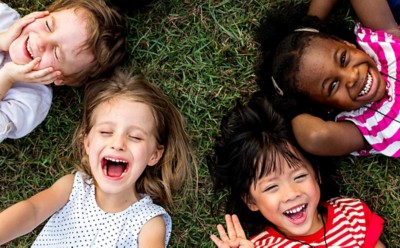 Group of kindergarten kids lying on the grass at park and relax with smiling