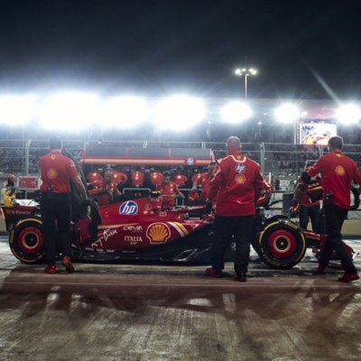 Crew gathers around race car under stadium lights - Leading the future of driving in a human-machine world | DXC Technology Insights  