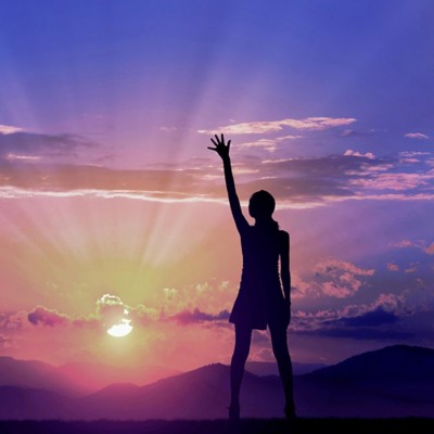 Woman reaching up gazing at brilliant sunset