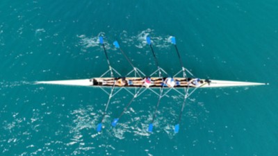  Aerial view of four rowers in a sport boat on emerald water | DXC Technology