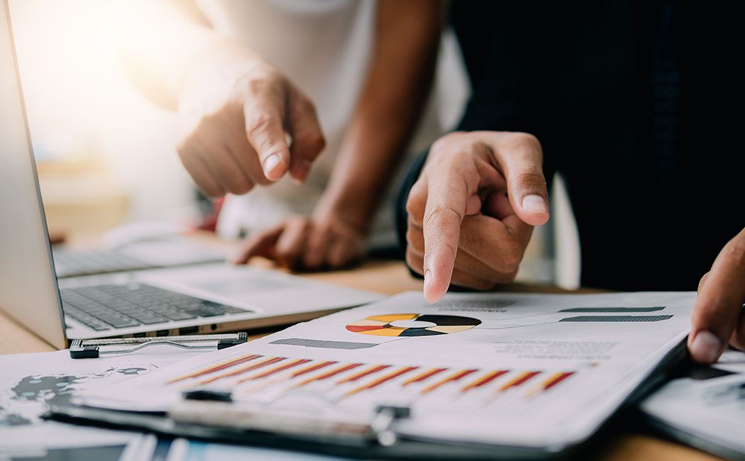 Team analyzing charts and reports near a laptop, reviewing data during a Salesforce data migration process to support an accurate migration plan.