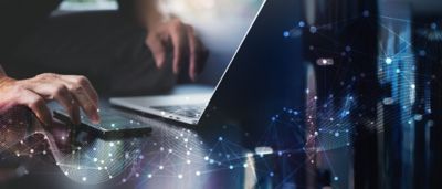 Man using mibile phone and laptop, representing Market Link in Commercial & Specialty Insurance​ | DXC