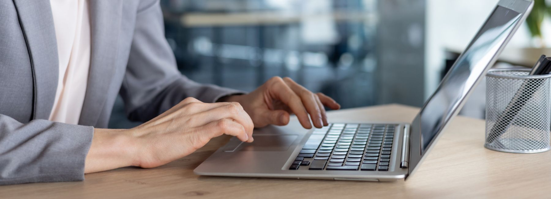 Mature woman businesswoman typing on a laptop in a modern office setting. Her focused expression highlights productivity and professionalism, embodying concepts of business and technology.