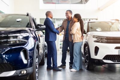 African American couple shaking hands with car dealer in showroom | DXC Technology