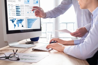 Team of financial people discussing a business analytics (BA) or intelligence (BI) dashboard on the computer screen showing sales and operations data statistics and key performance indicators (KPI)