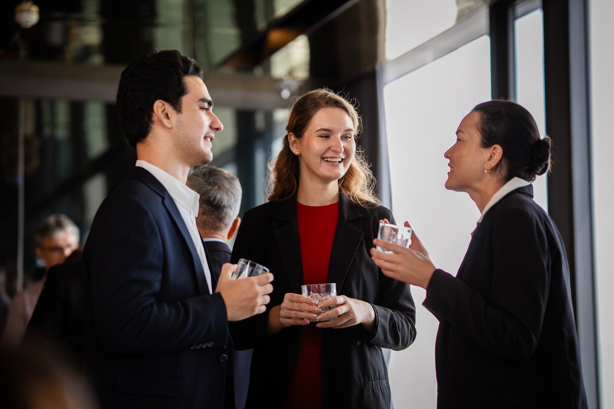 Informal business conversation at a party environment, reflecting collaboration, leadership, and modern workplace culture. Business people relaxed talk at party on rooftop restaurant.