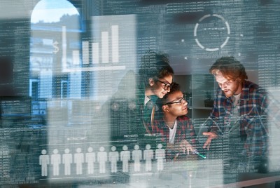 Young engineers meeting with computer code reflected on glass wall