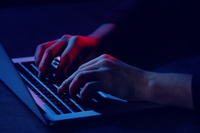 Professional hacker with laptop sitting at table, closeup