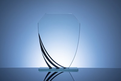 Elegant blank glass shield trophy on dark blue background ready to be engraved for the winner of a competition or race