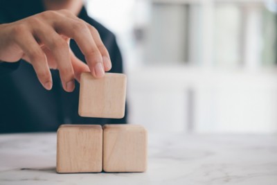 Business concept of success process. Hand holding blank wood cube block on top pyramid.
