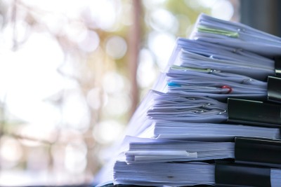 Stacks of legal papers on desk in bright office, Generative AI, Regulatory AI Engine | DXC Technology