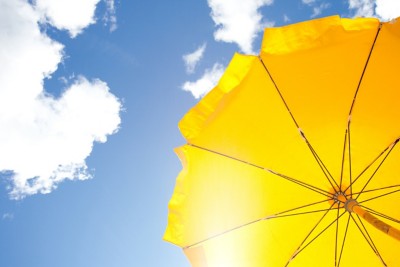 yellow umbrella on blue sky with clouds