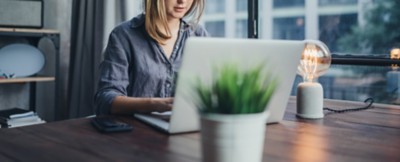 Young woman working on laptop. Freelancer at remote work. Female student learning on-line via computer. Blogger or journalist writing new article.