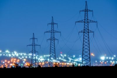 Three electricity pylons and power lines outside a town at night, U.S. energy company, Applications | DXC Technology