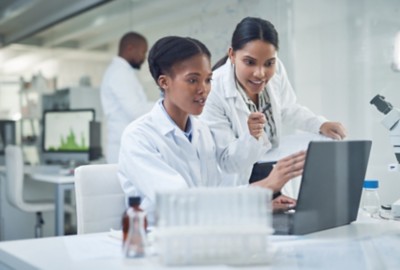 Two life sciences technicians consulting in front of computer screen in lab, Life Sciences | DXC Technology Software