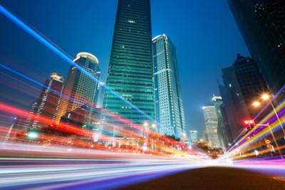 City with tall buildings and colorful streams of light suggesting car traffic