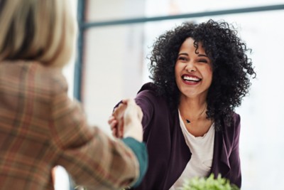 Handshake with a happy, confident and excited business woman or human resources manager and a female colleague, partner or employee. An agreement, deal or meeting with a coworker in the boardroom.