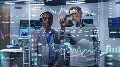 Two male data analysts reviewing digital charts on a clear screen, AI and data analytics in banking | DXC Technology Insights