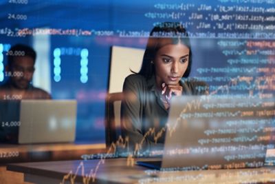 Woman working on laptop in office managing privileged access to secure critical data systems, Zero trust solutions | DXC Technology