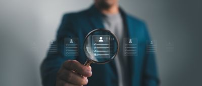 Man in blue jacket holding magnifying glass with digital data overlay, Digital Banking | DXC Technology Insights