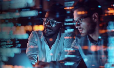 Two male engineers reviewing code on a screen