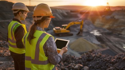 construction engineers inspecting mining site at sunset with digital tablets for project management