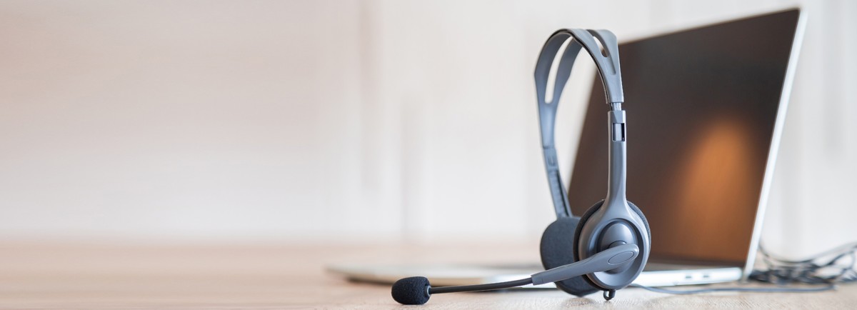 Communication support, call center and customer service help desk. VOIP headset on telephone keyboard.