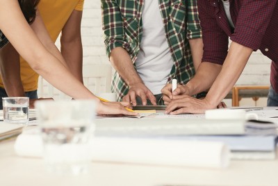 Cropped image of young people discussing idea on document on the table