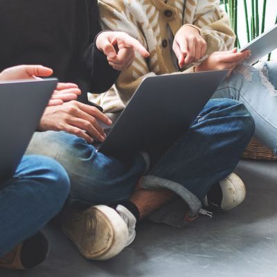 three employees sitting on floor working on laptops, Dell Technologies | DXC Technology