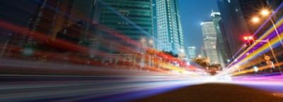 City with tall buildings and colorful streams of light suggesting car traffic