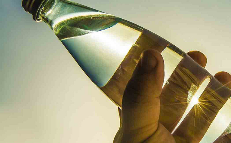 close-up of a tilted glass bottle with clear liquid
