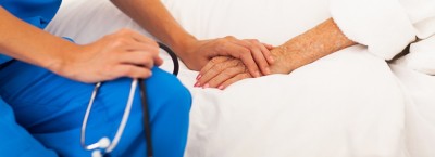 medical doctor holing senior patient's hands and comforting her