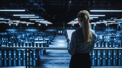 Data Center Female Programmer and Maintenance IT Specialist Overlooking Cloud Computing Server Farm. System Administrator Working on Cyber Security for Iaas, saas, paas. Back View Shot