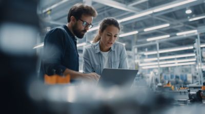Male and female AI engineers discussing a project in a technical workspace, AI Engineering & Solutions | DXC Technology