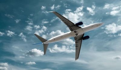 Plane flying in bright blue sky dotted with clouds, the future of AI in the aerospace industry | DXC Technology Insights