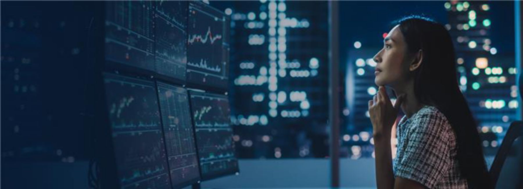 Female financial analyst work at multiple screens in city office at night, Trading Platform Health Checks | DXC Technology