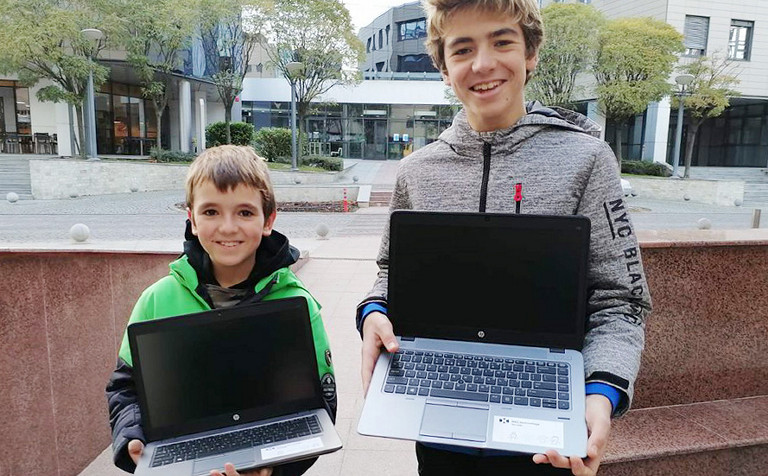 2 boys holding computer they received from DXC