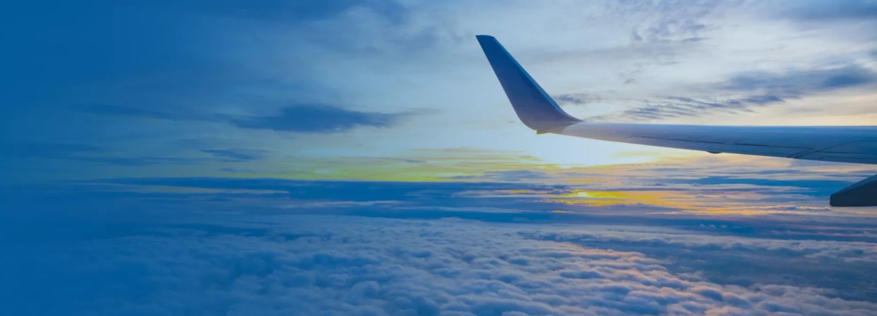 Tip of aircraft wing against blue sky and setting sun | DXC Technology Customer Stories 