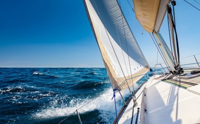 White sailing boat at open sea in sunshine