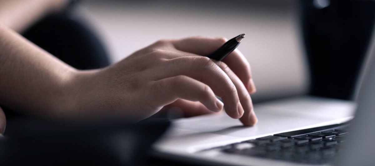 hands on computer with pencil, Hogan Academy, Hogan Core Banking Platform | DXC Technology Platforms