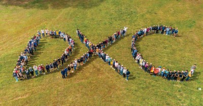 People standing in open field to form the letters DXC