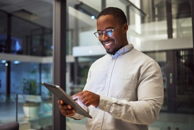 Night business. tablet and black man typing and reading information online doing research and smiling at good results working late. Happy male on internet for marketing strategy in Nigeria office.