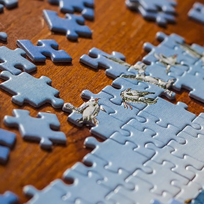 Partially solved jigsaw puzzle with scattered puzzle pieces on the table