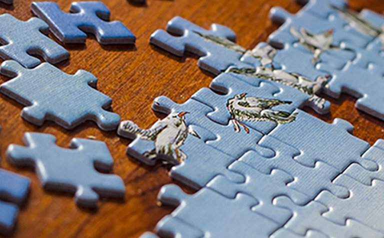 Partially solved jigsaw puzzle with scattered puzzle pieces on the table