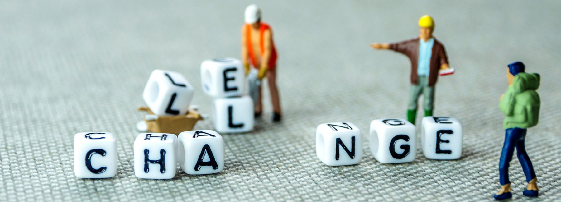 Removing white cubes with letters l and e of the word challenge creating new word change on grey background with miniature figurines