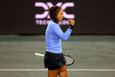 Tennis player fist-pumping on the court with DXC logo in background