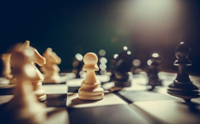 Image of the white and black pieces on a chess board, with shallow depth of field.