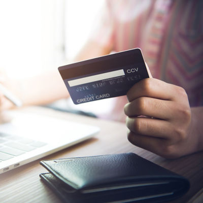 hand holding credit card at laptop