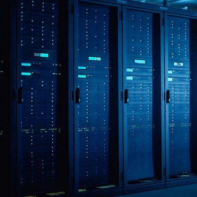 In Data Center: IT Technician Running Maintenance Programme on Laptop, Controls Operational Server Rack Optimal Functioning. Modern High-Tech Telecommunications Operational Data Center in Neon Lights.