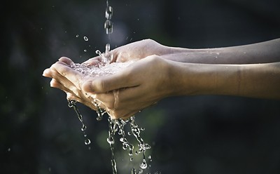 closeup water flow to hand of women for nature concept on the garden background.
